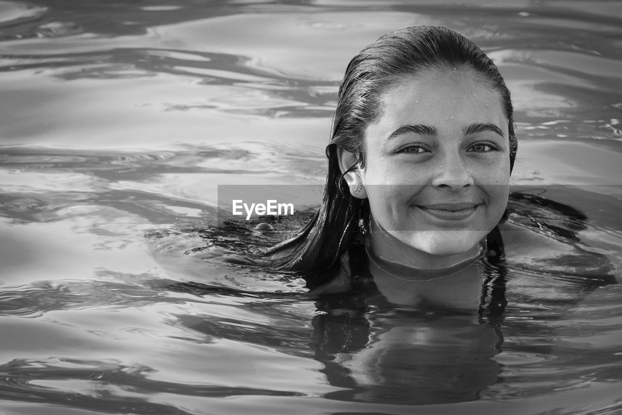 Portrait of smiling young woman swimming in lake