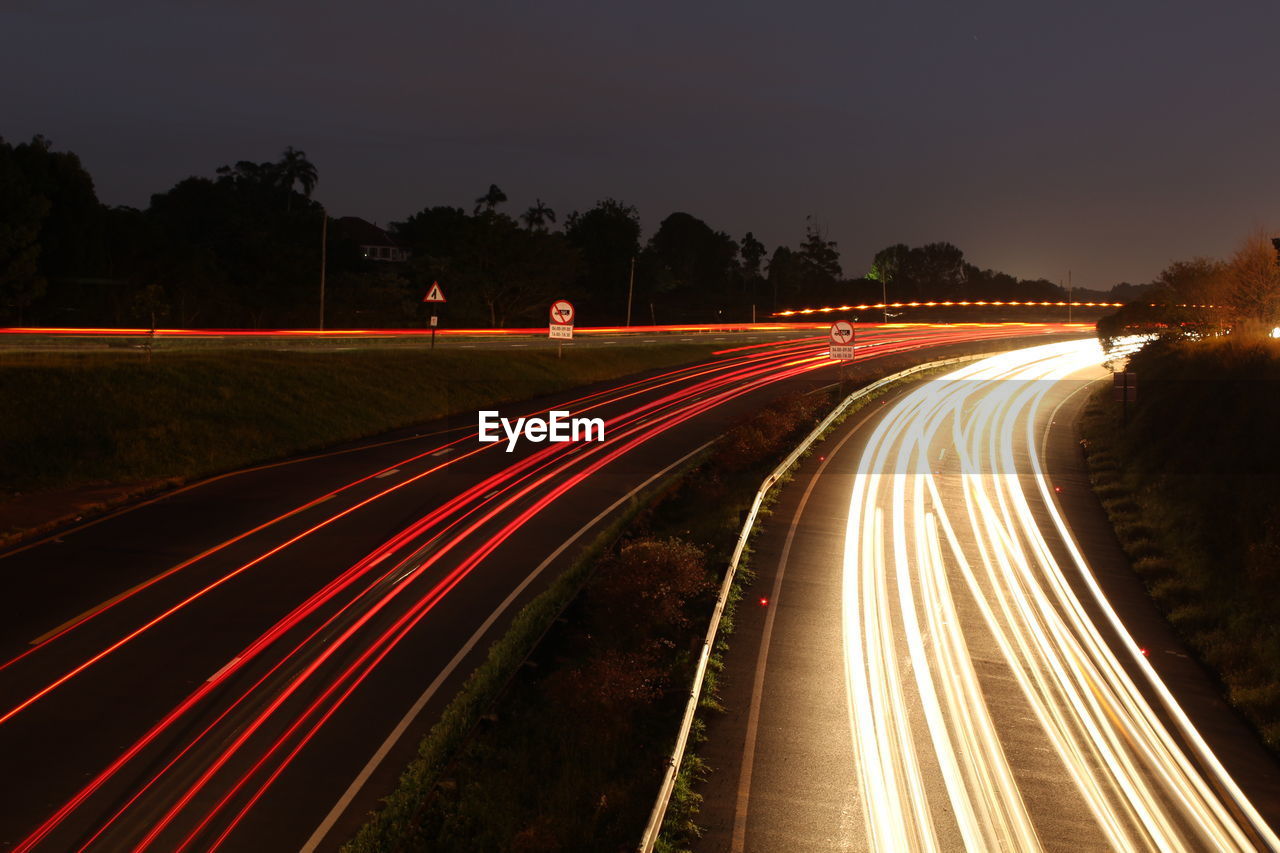 Light trails on road against sky at night