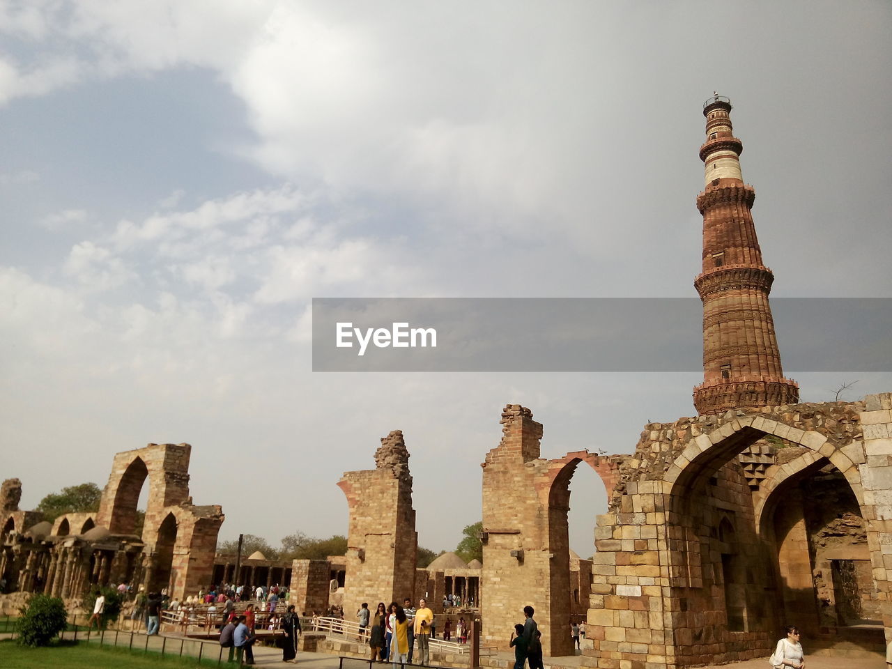 Low angle view of qutub minar against cloudy sky