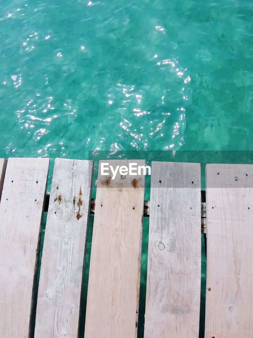 HIGH ANGLE VIEW OF WOODEN POST ON PIER BY SEA