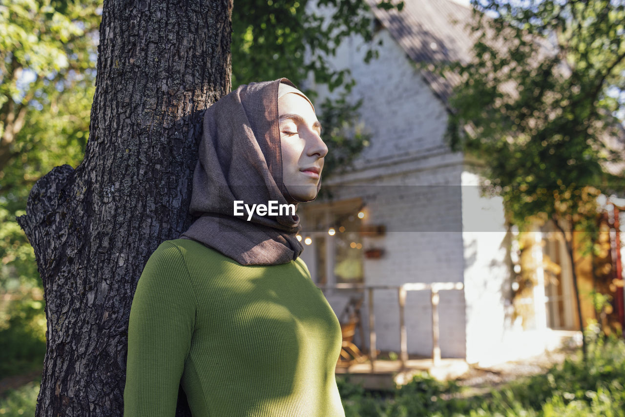 portrait of woman standing against tree