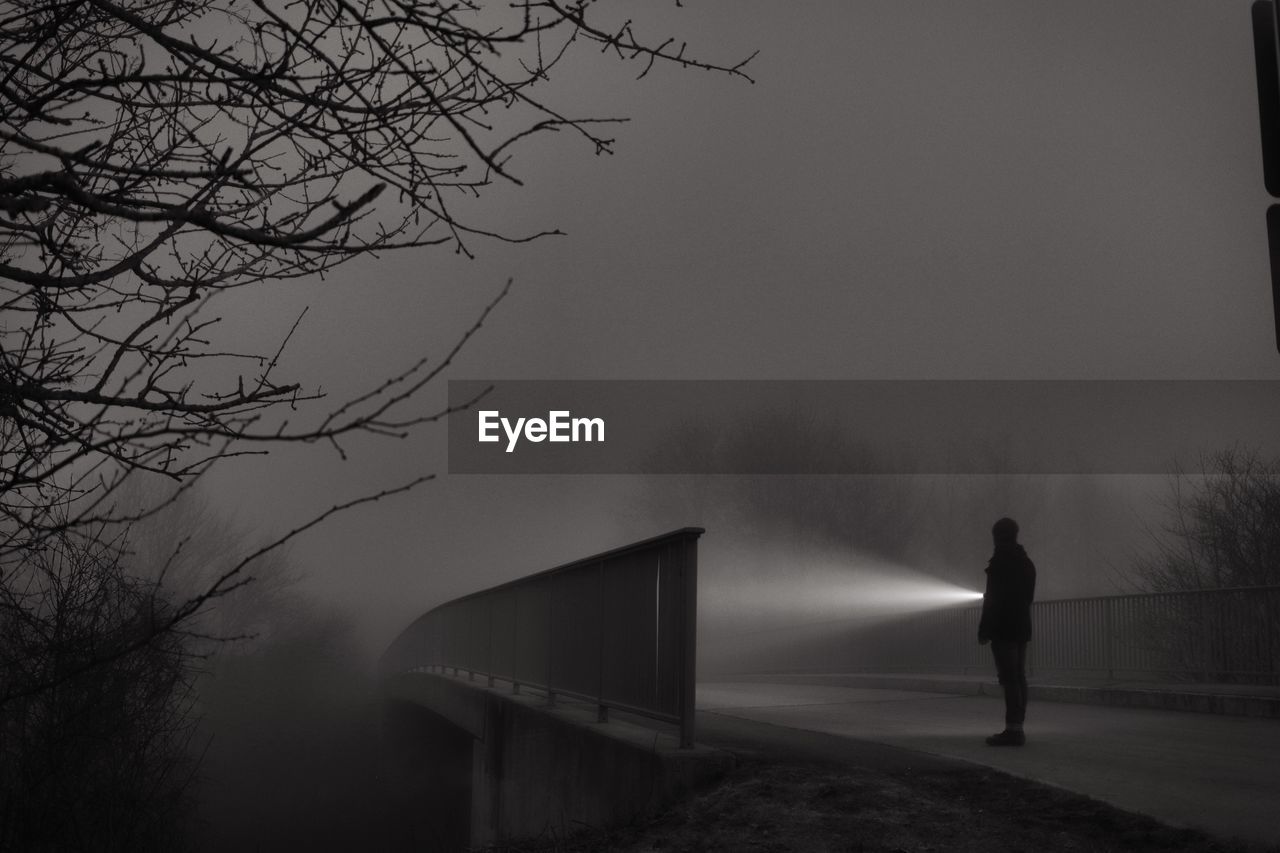 Man with flashlight standing on road at night