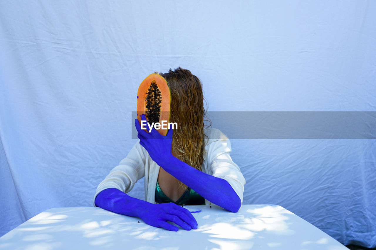 HIGH ANGLE VIEW OF WOMAN SITTING ON BLUE WALL