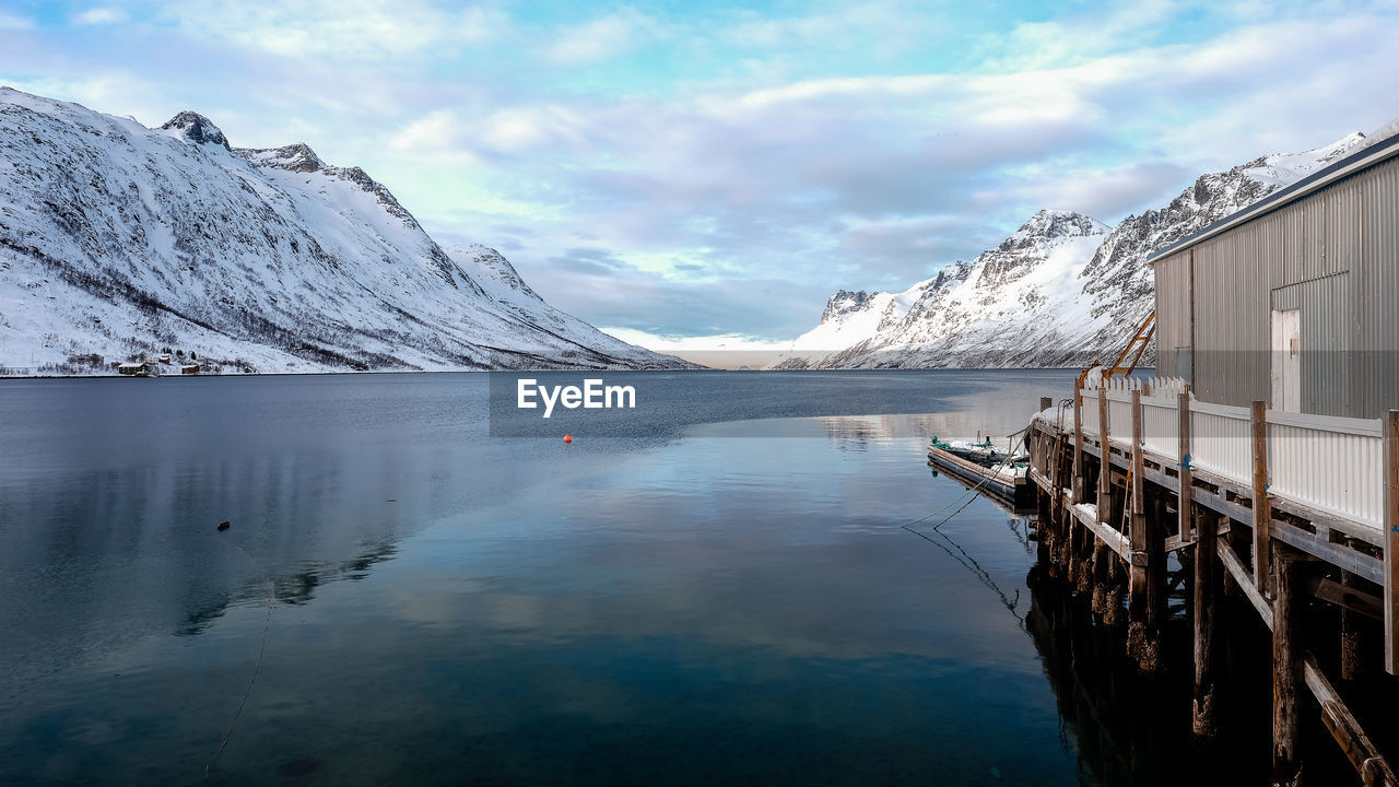 Scenic view of lake by snowcapped mountains against sky