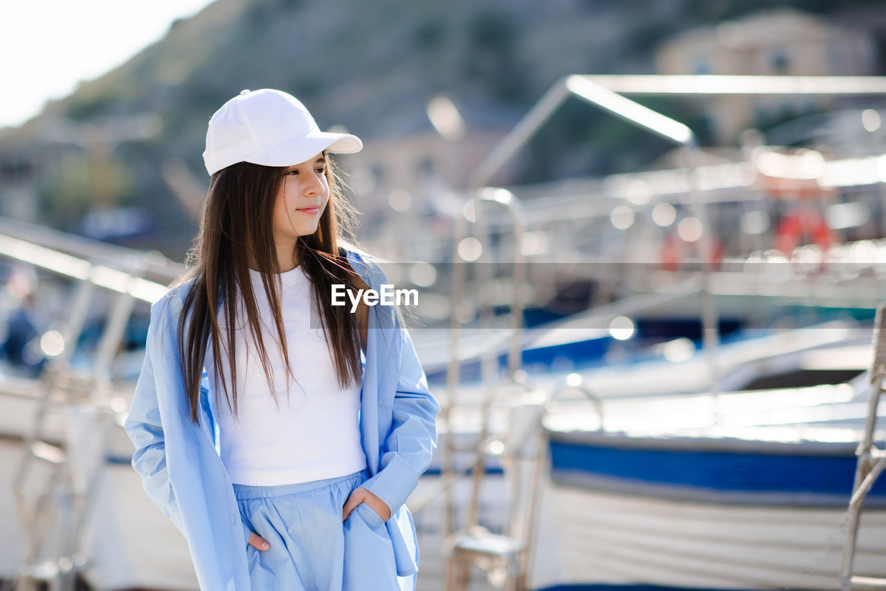 side view of young woman looking away while standing in city