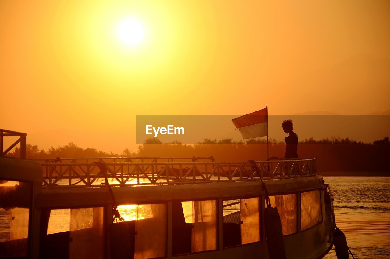 MAN IN BOAT AGAINST SEA DURING SUNSET