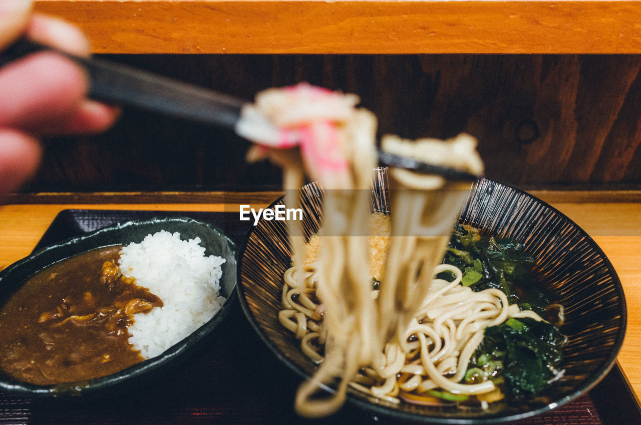 Cropped image of hand holding noodles in restaurant