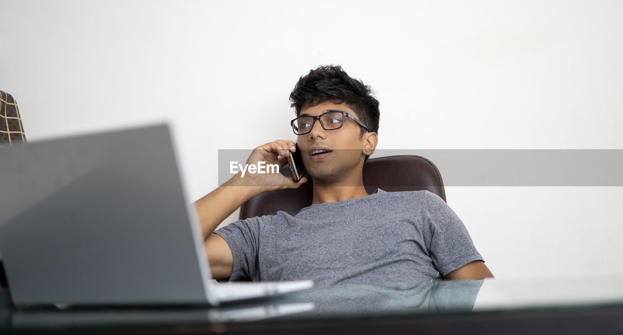 Indian boy talking over phone while working in office. person