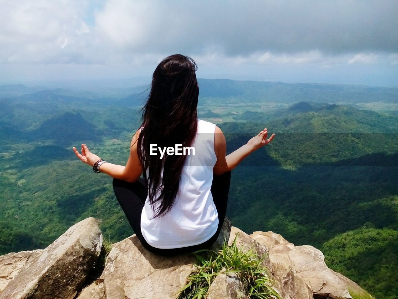 Rear view of woman doing yoga on cliff