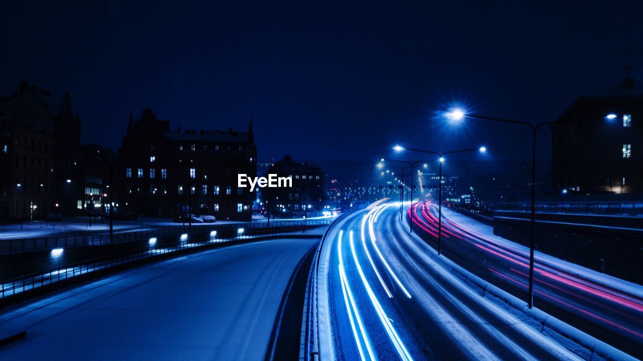 Light trails on road against sky at night