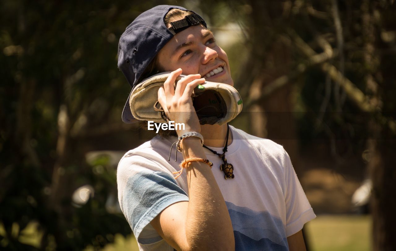 Close-up of cheerful man looking up while talking on shoe