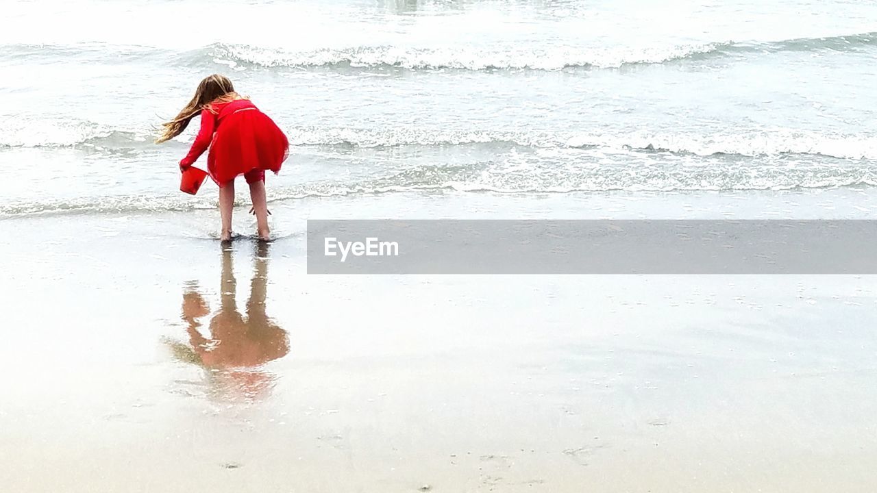 REAR VIEW OF WOMAN STANDING IN WATER