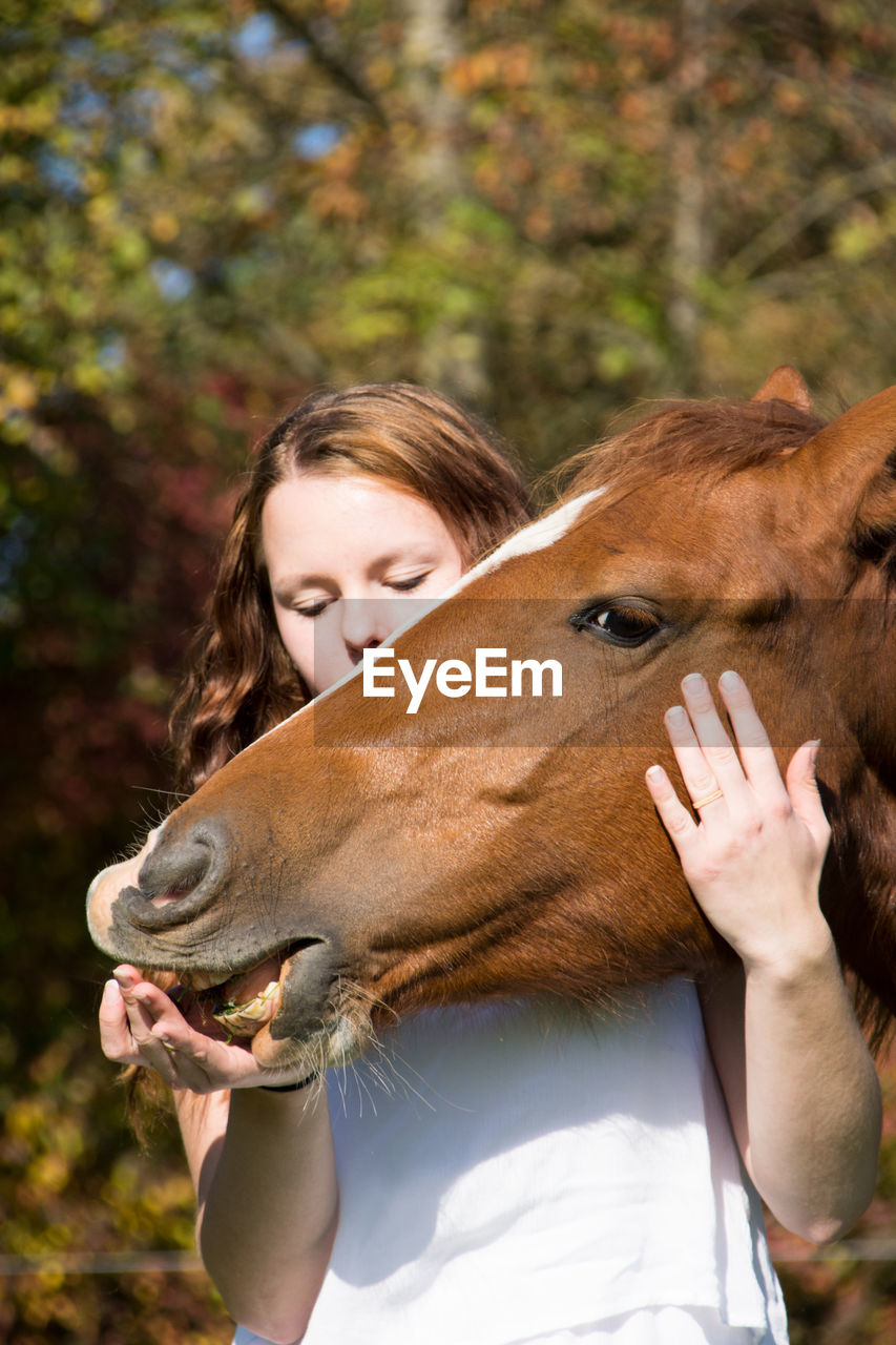 Young woman stroking horse at farm