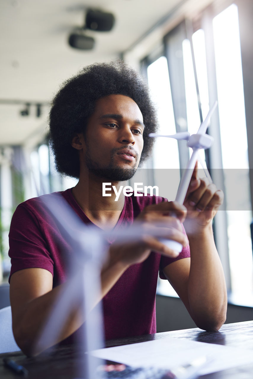 Young man looking at windmill model in office