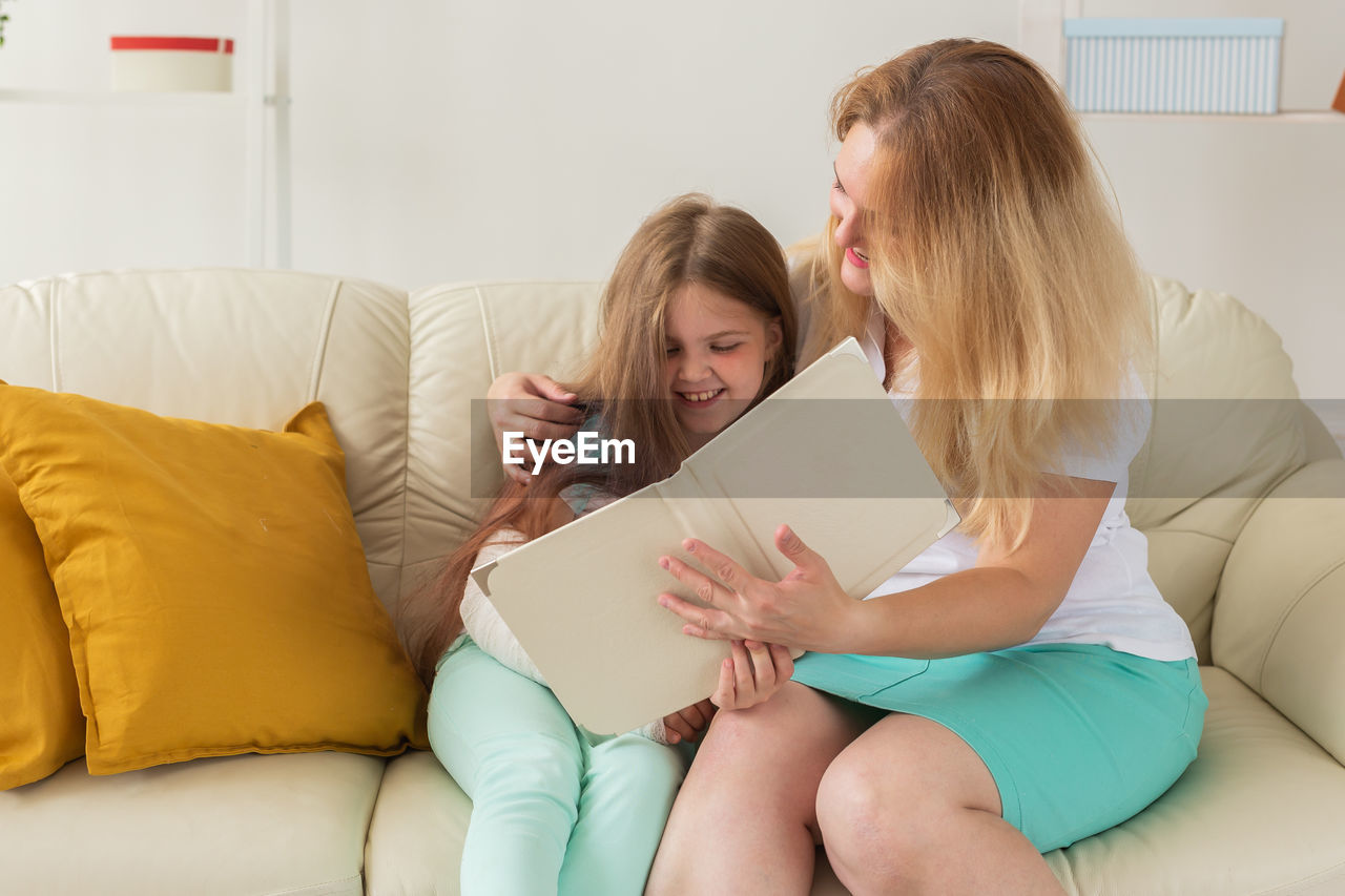 Friends sitting on sofa at home