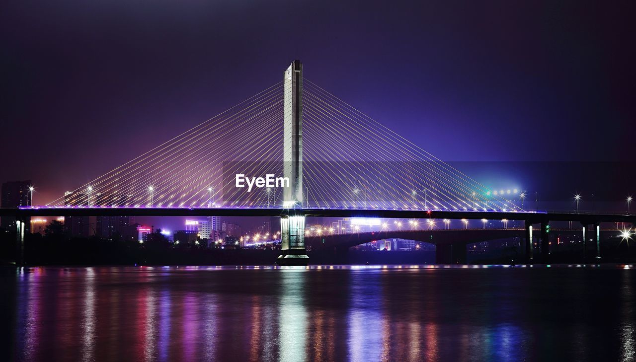 Suspension bridge with city lit up at night