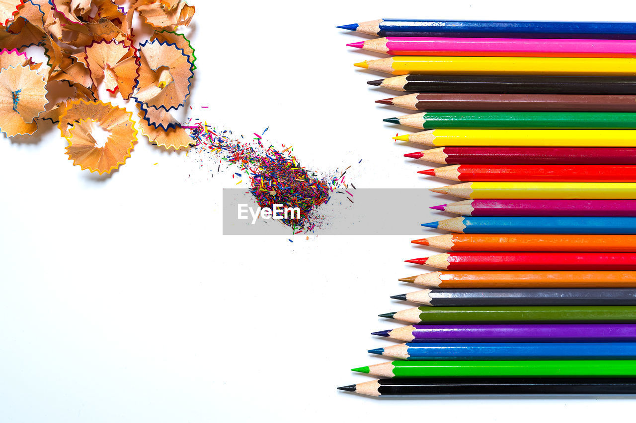 HIGH ANGLE VIEW OF COLORED PENCILS ON WHITE TABLE