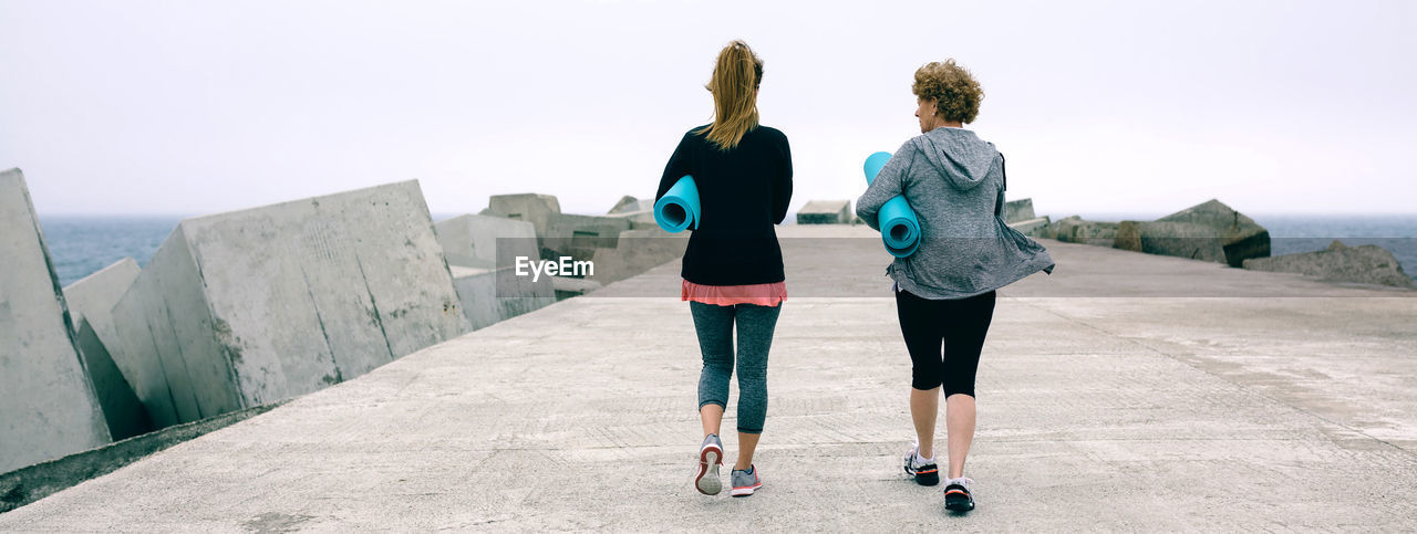 Mother and daughter with exercise man walking on pier