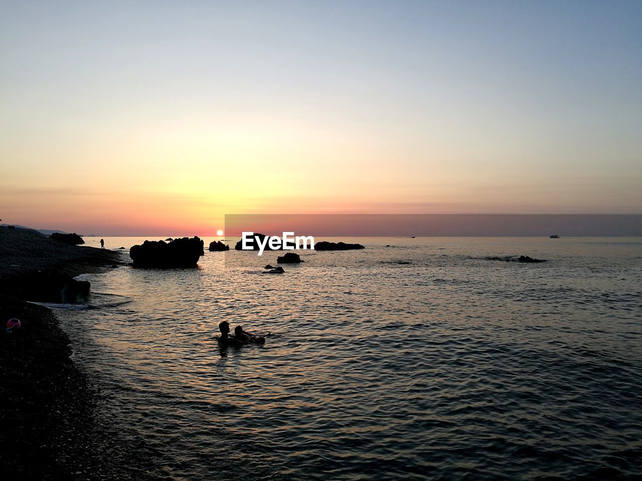 SILHOUETTE PEOPLE IN SEA AGAINST CLEAR SKY