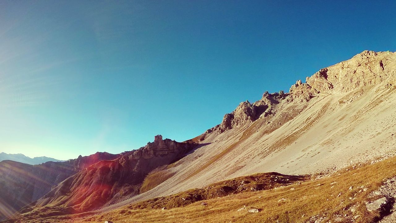 View of barren landscape against clear blue sky