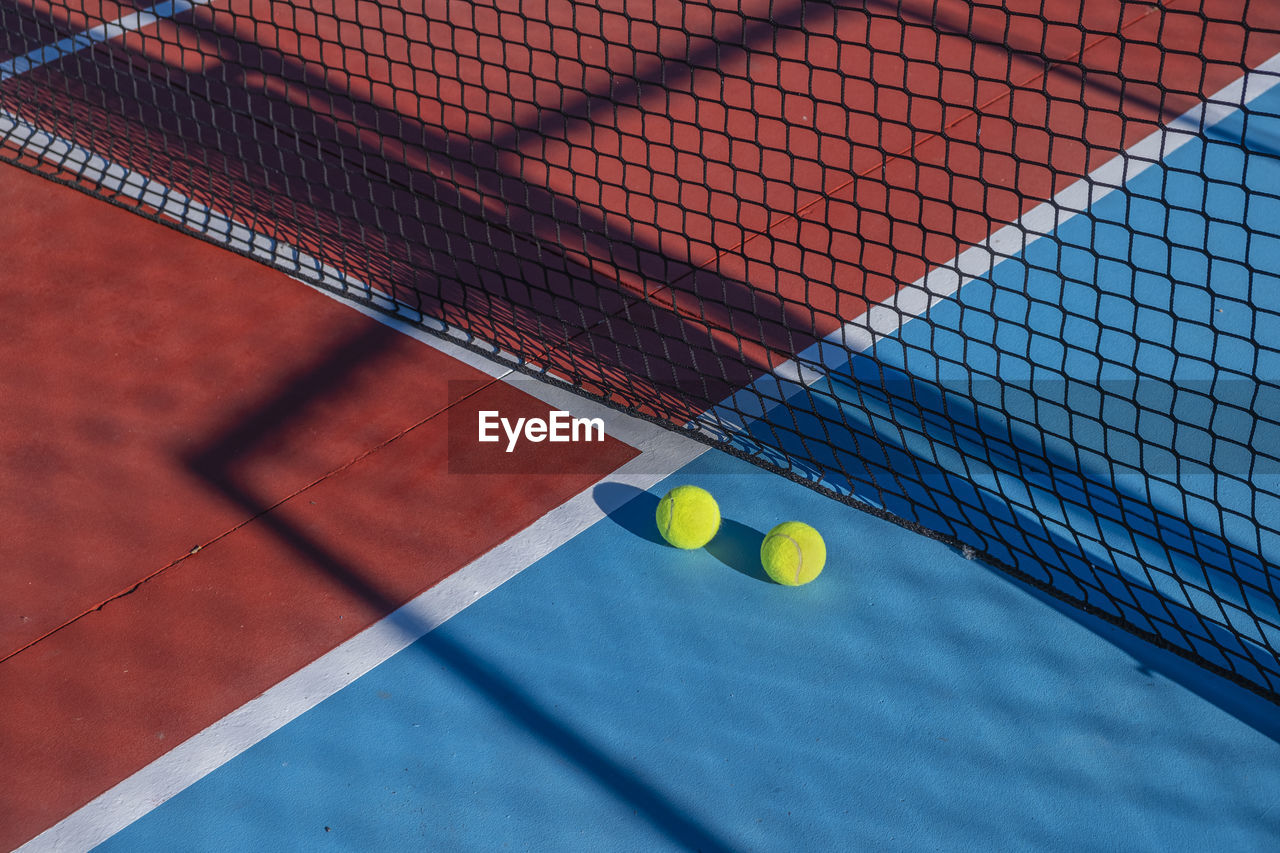 Two balls near the net of a red tennis court