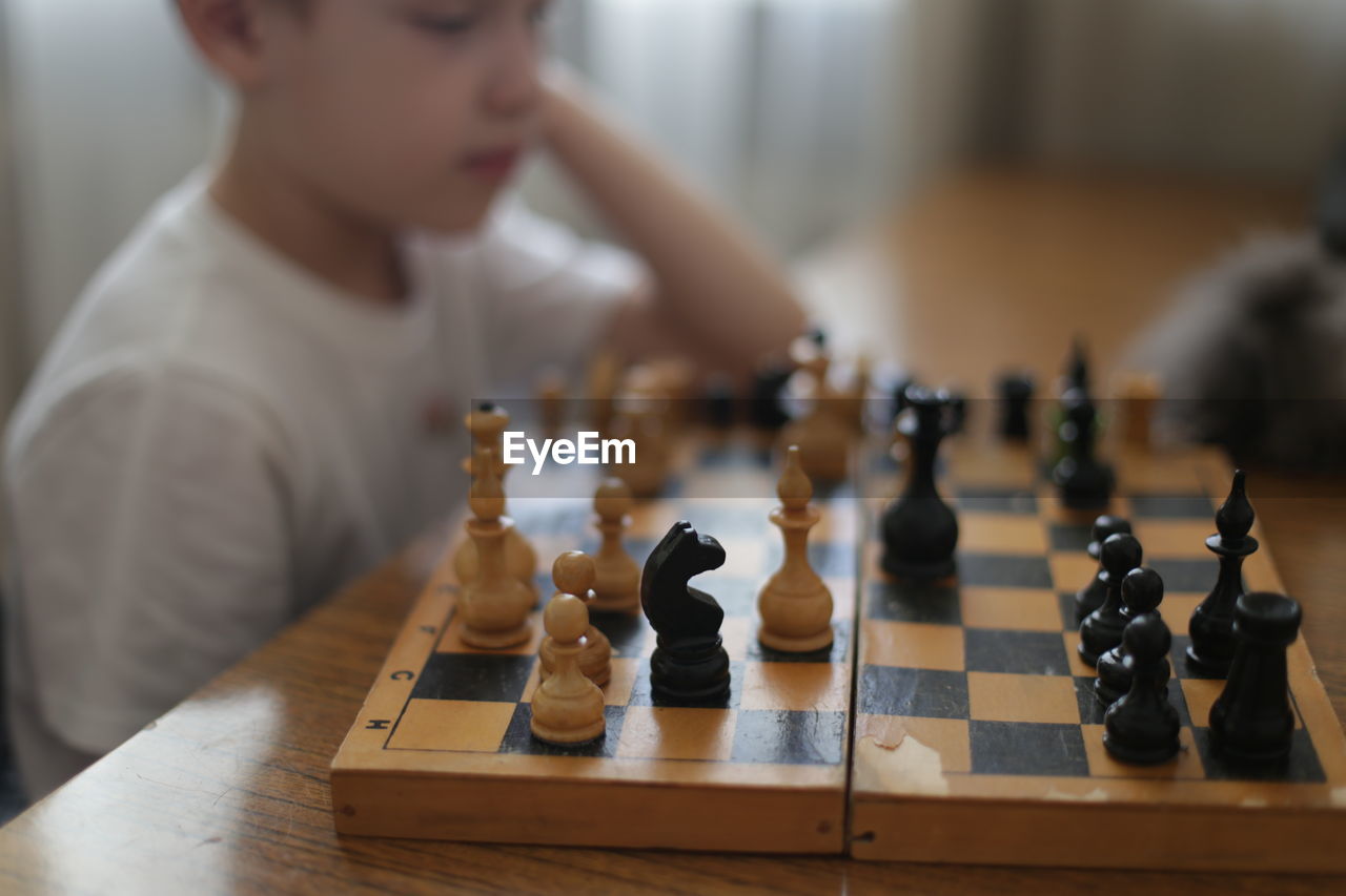 Midsection of boy playing chess at home