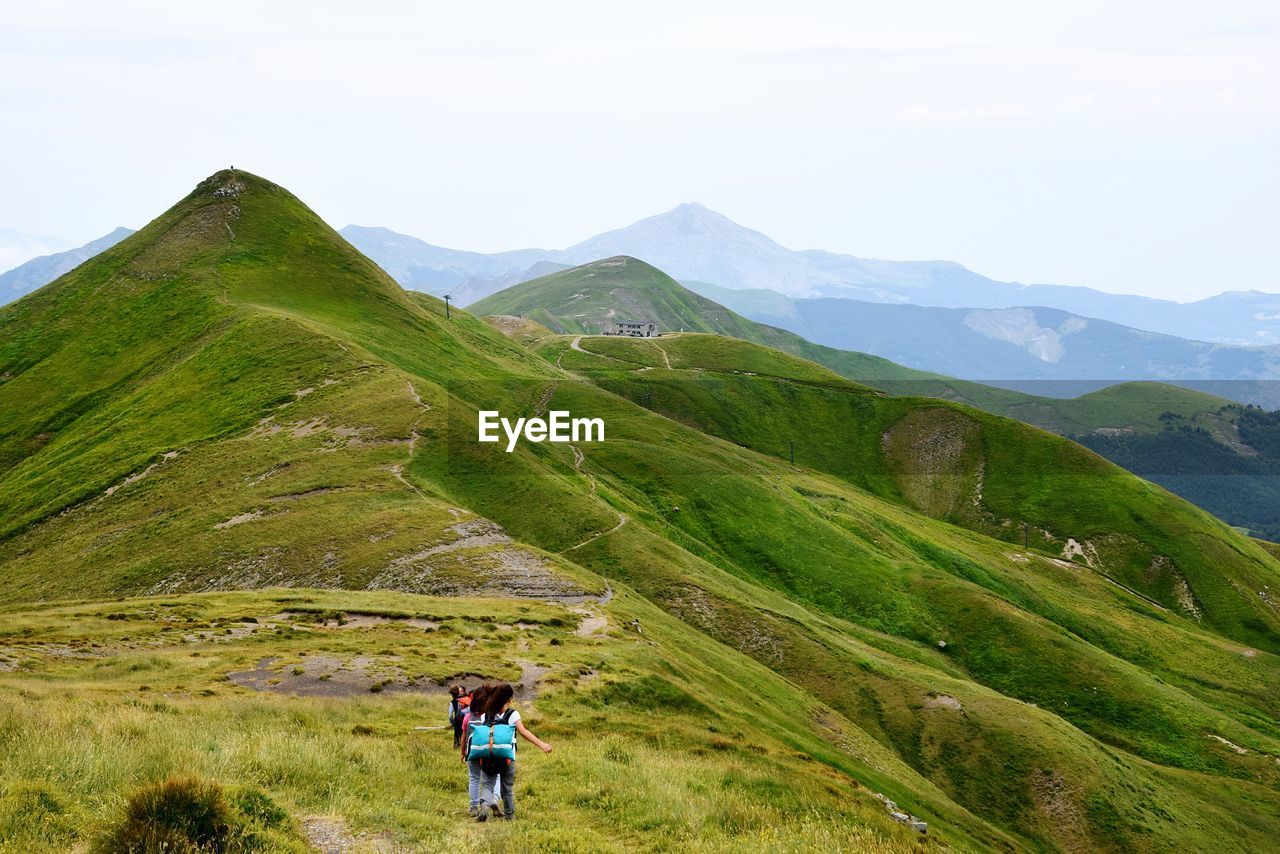 Rear view of hikers walking on mountain against sky