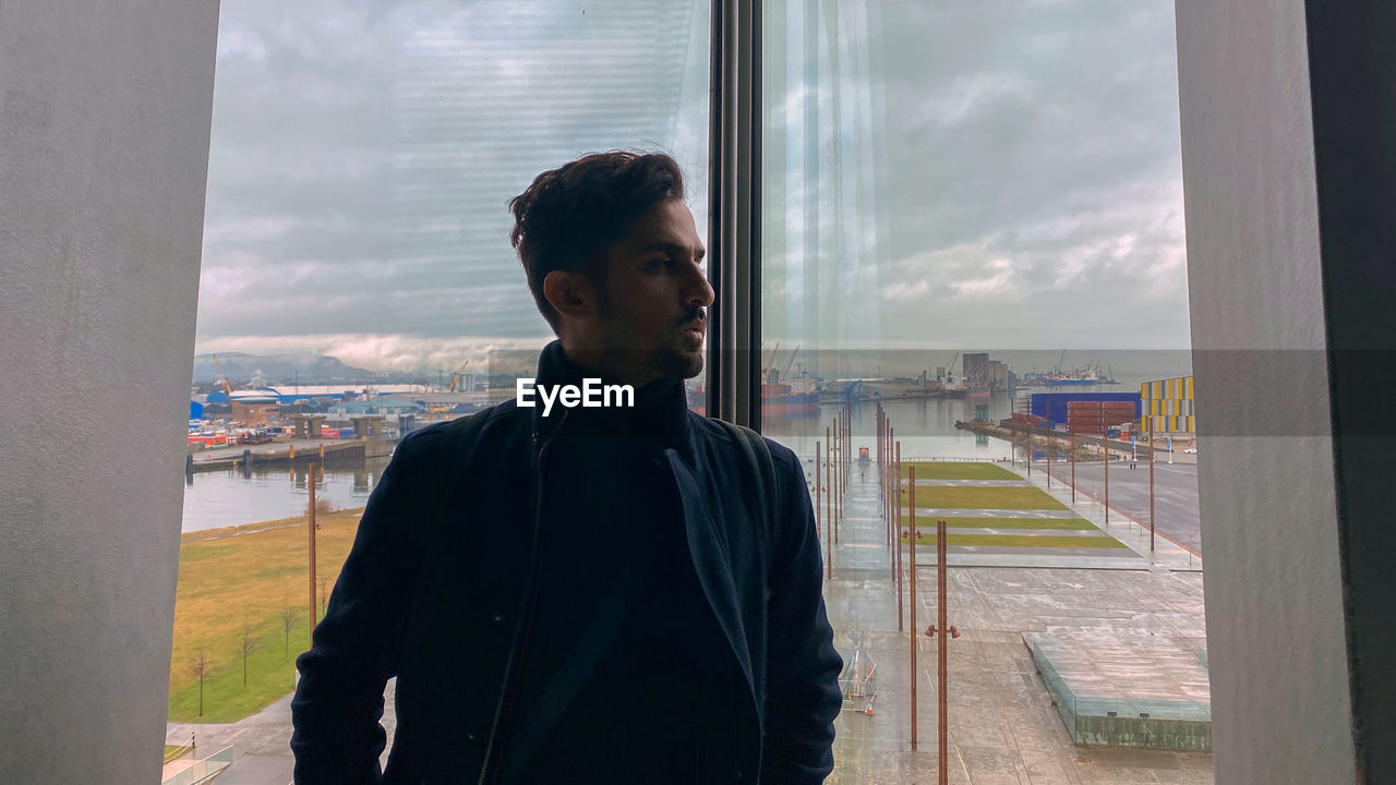 Man looking at cityscape seen through glass window