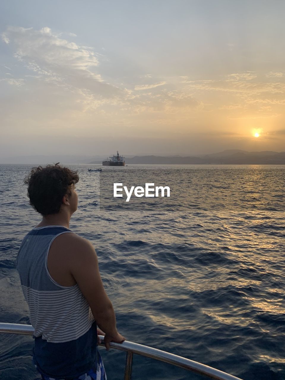 Rear view of man looking at sea against sky during sunset