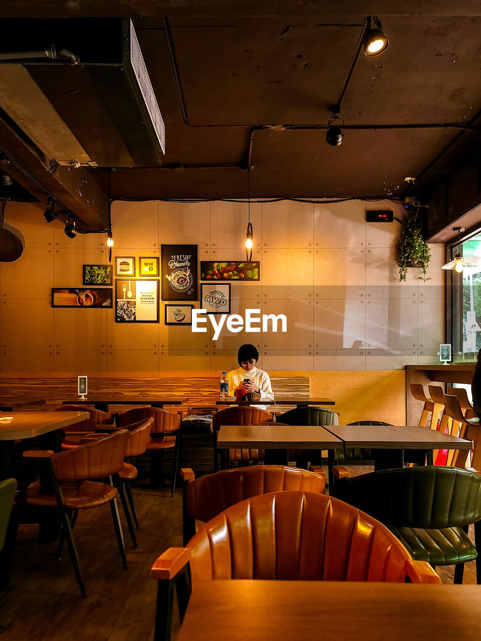 restaurant, indoors, table, food and drink, business, bar, seat, adult, cafe, interior design, chair, bar counter, one person, furniture, café, occupation, lighting equipment, lighting, illuminated, food and drink establishment