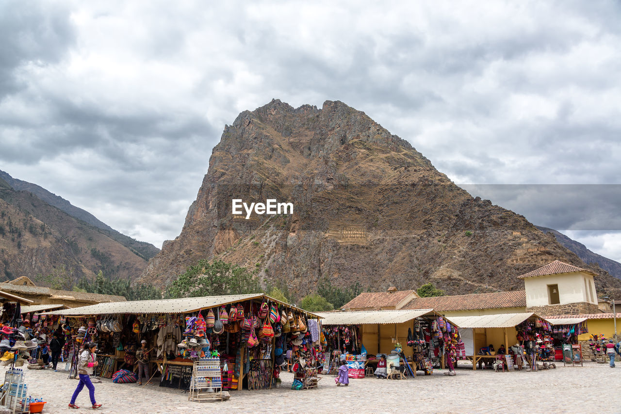 TOURISTS ON TOP OF MOUNTAINS AGAINST CLOUDY SKY