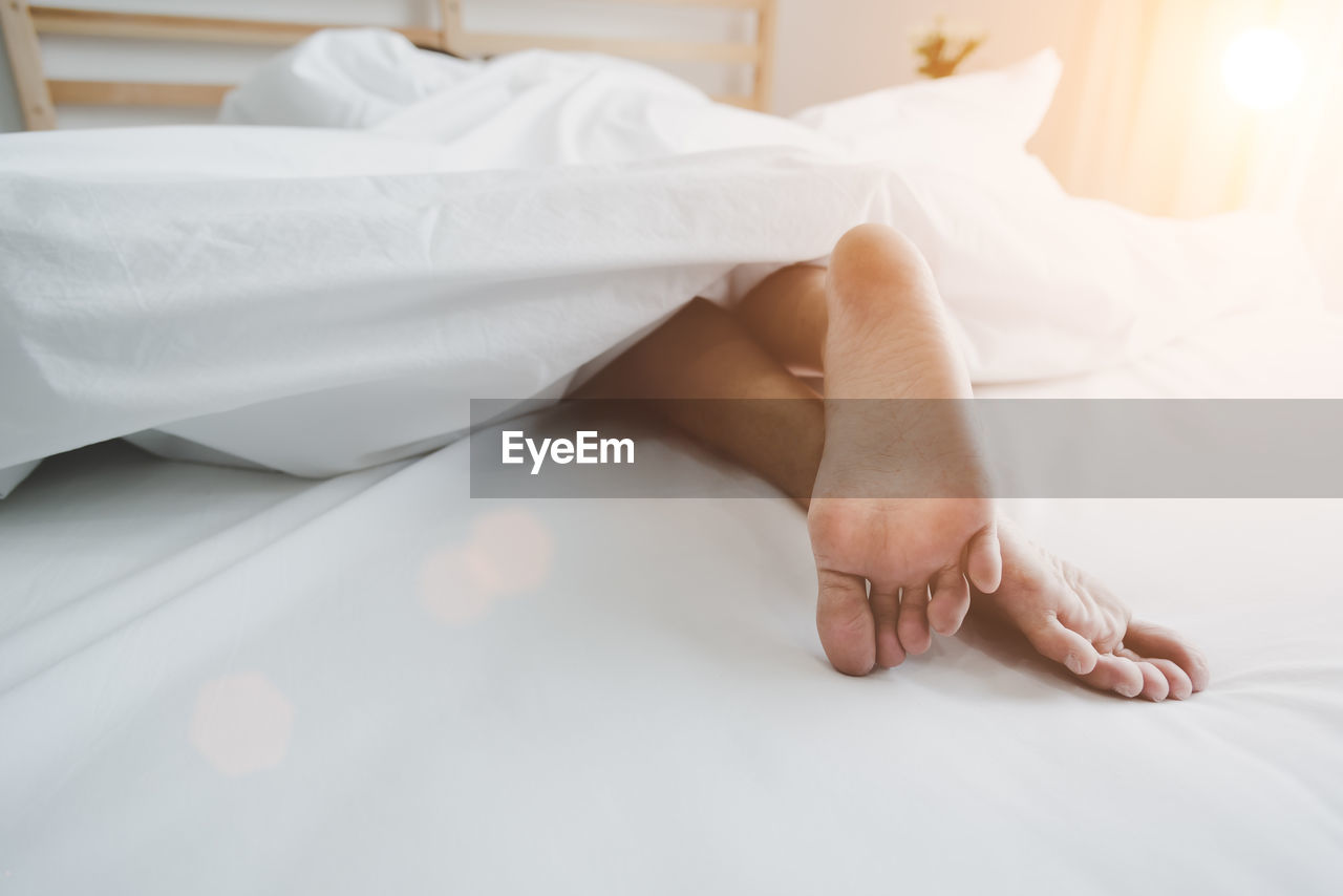 Low section of woman lying on bed