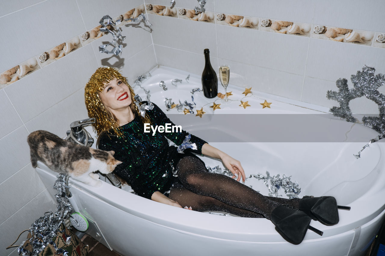 New years party birthday celebration. happy young woman in evening dress sitting in the bathtub