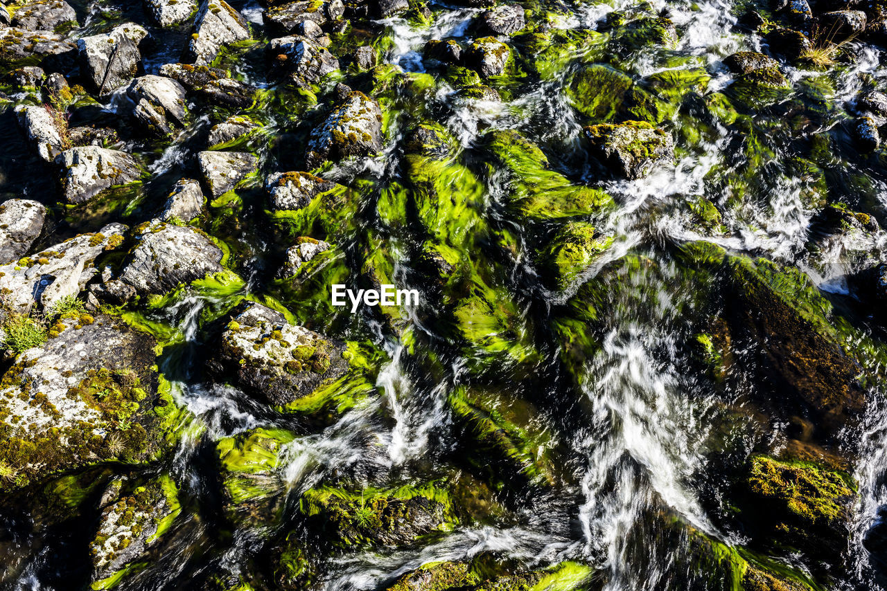 FULL FRAME SHOT OF WATERFALL WITH ROCKS IN BACKGROUND