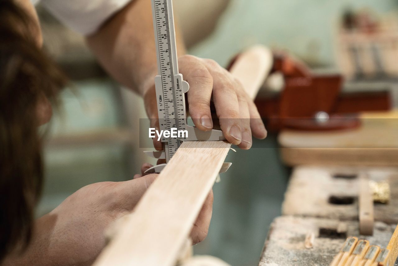 Cropped hands of man working on wood at workshop