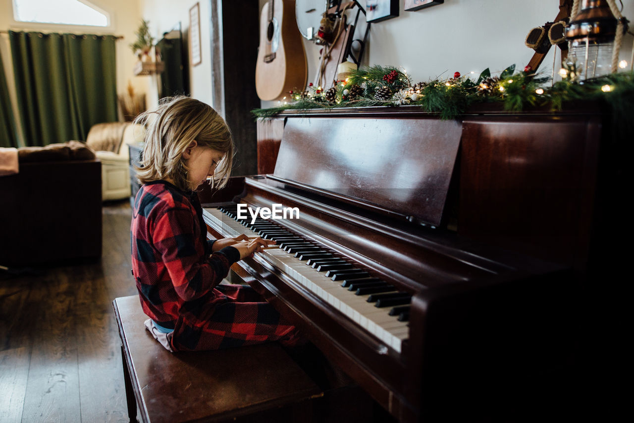 Little boy playing piano with christmas greenery
