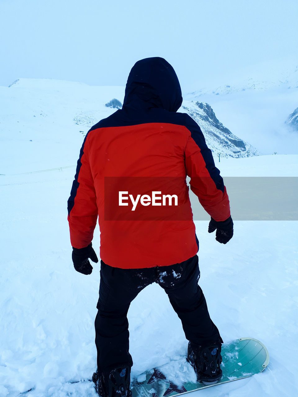 REAR VIEW OF BOY STANDING ON SNOW COVERED LANDSCAPE