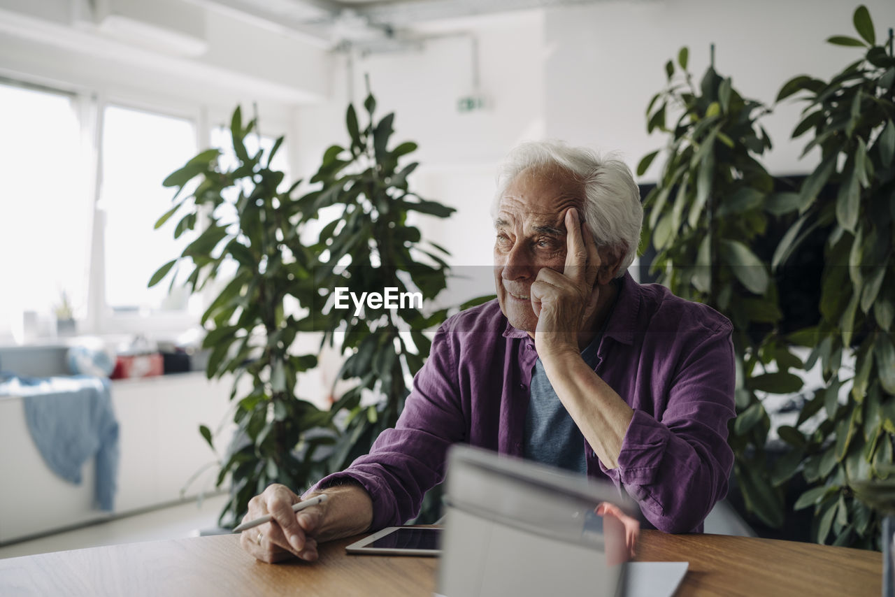 Thoughtful businessman with head in hand looking away while sitting at office