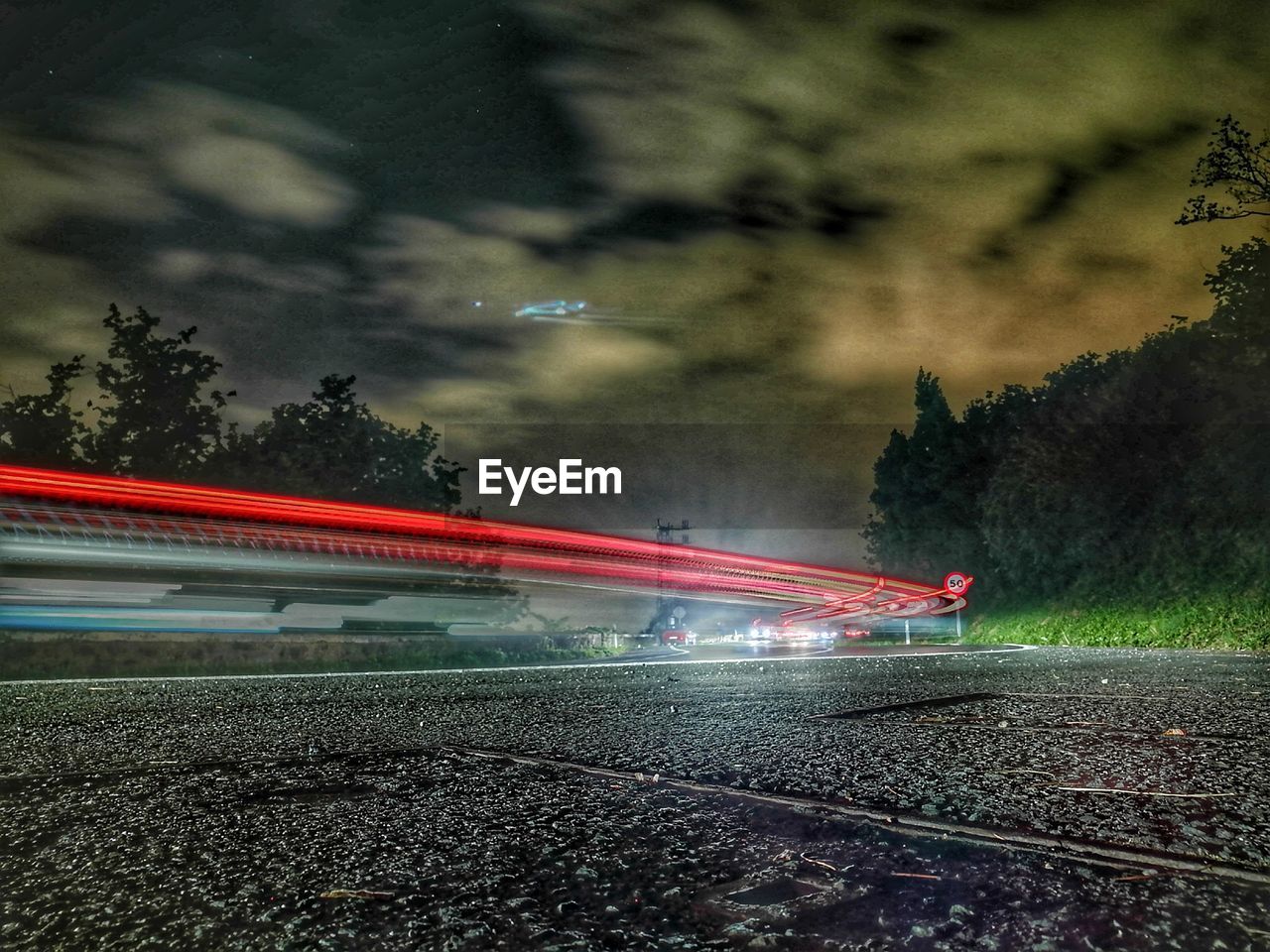 Light trails on road against sky at night