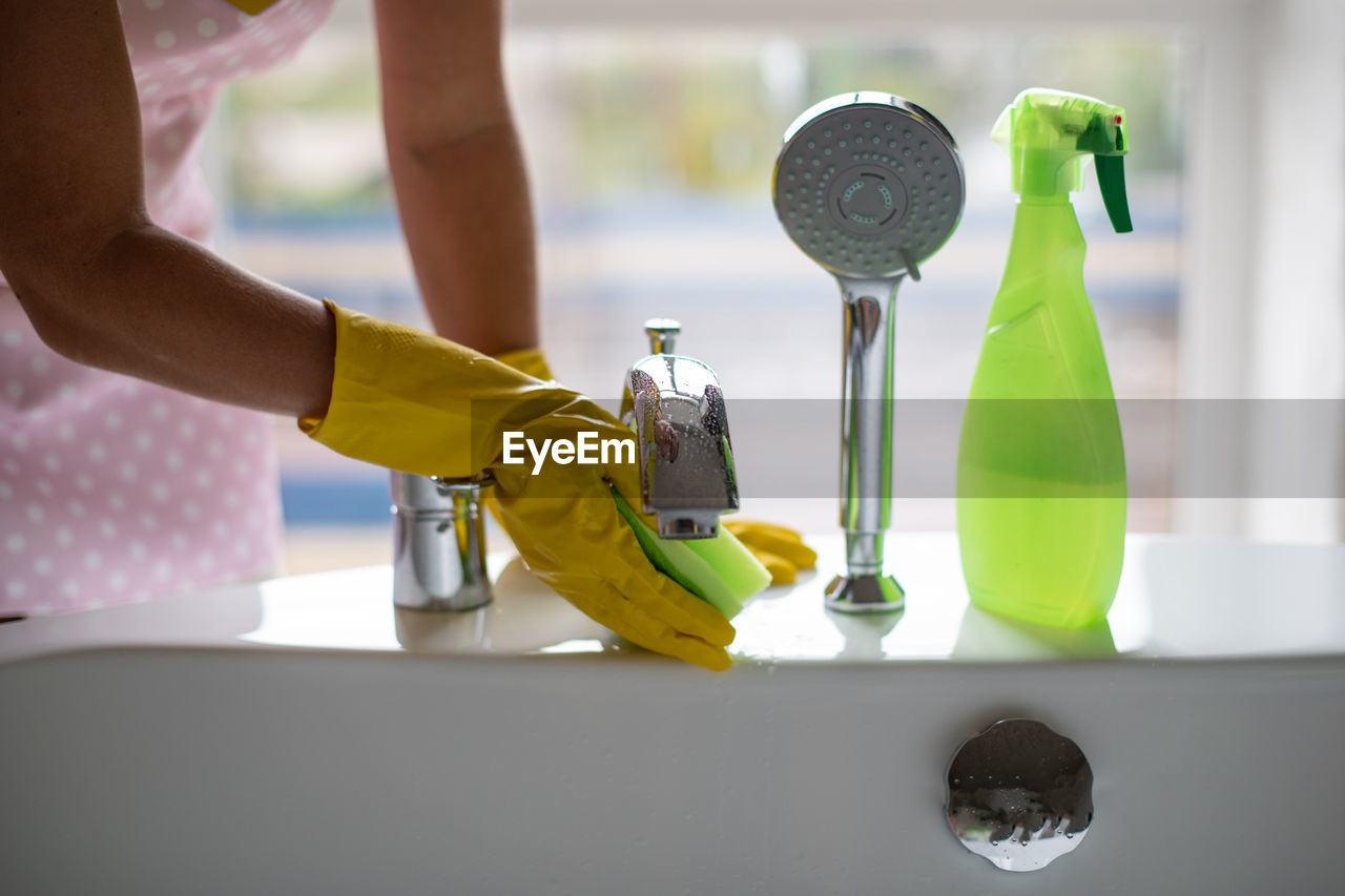 Cleanliness and hygiene at home. hand in green and yellow rubber gloves. rubbing  bathroom and taps