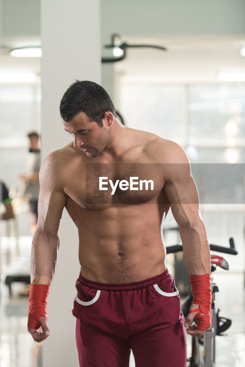 Muscular shirtless man standing in gym