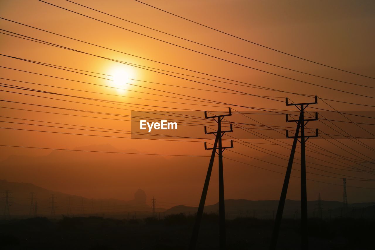 SILHOUETTE ELECTRICITY PYLONS AGAINST ORANGE SKY