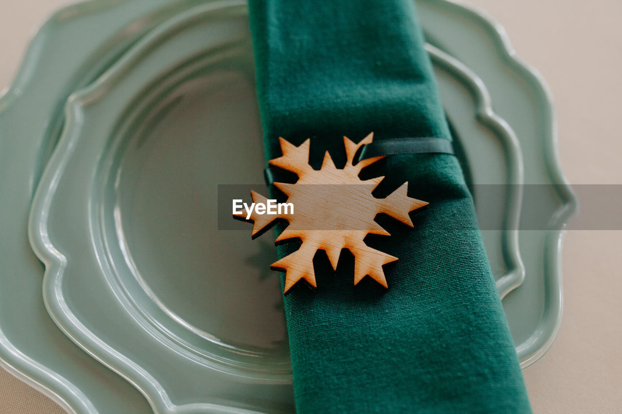 High angle view of wooden snowflakes napkin ring on teal blue plate