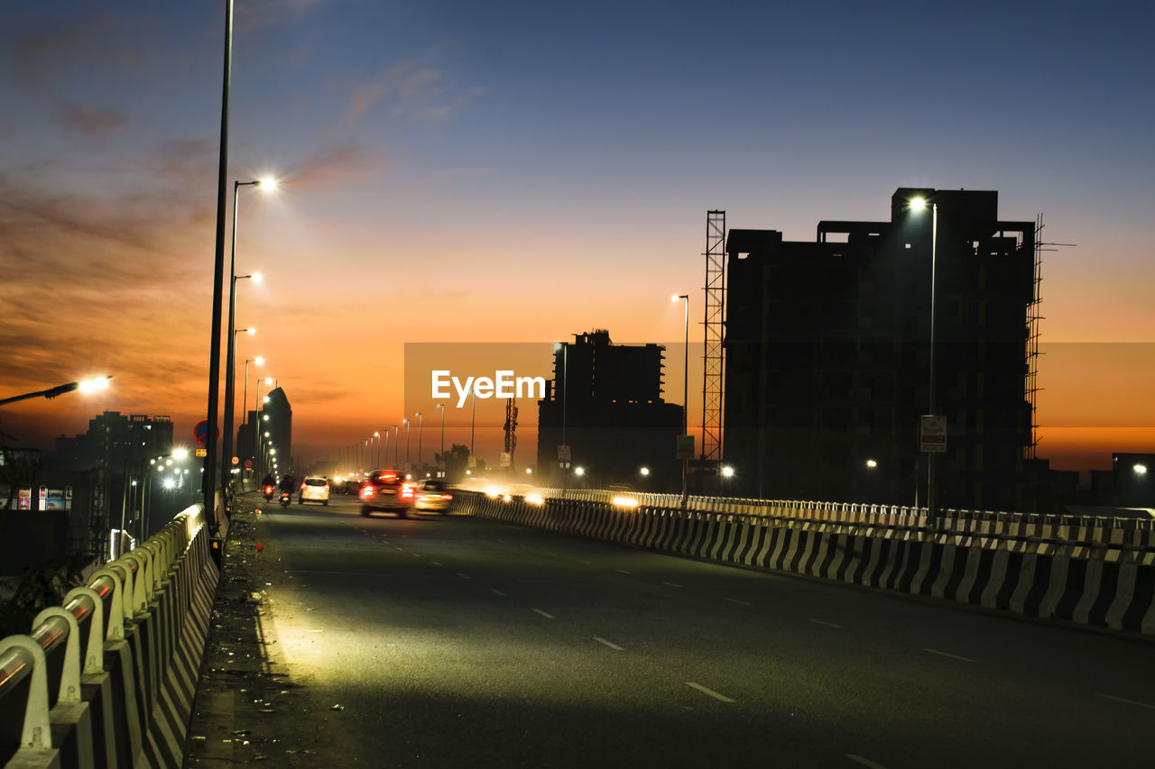STREET AMIDST BUILDINGS AGAINST SKY AT NIGHT