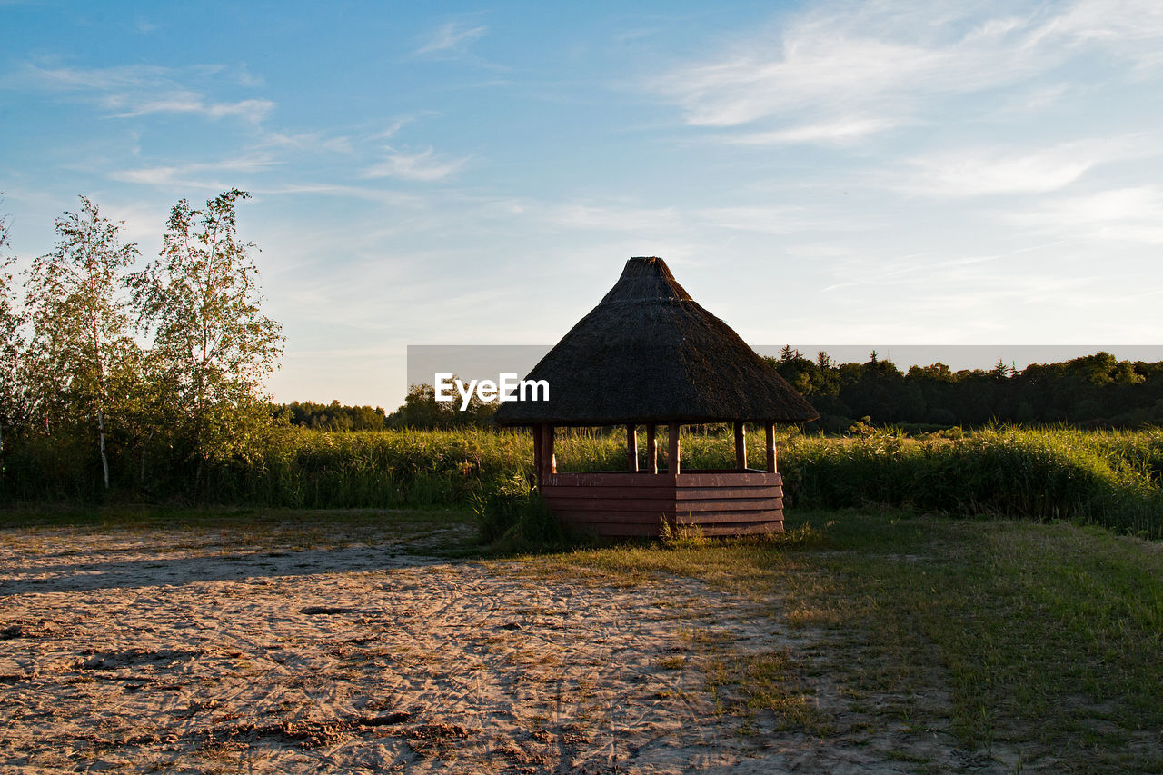 GAZEBO ON FIELD AGAINST SKY DURING SUNSET