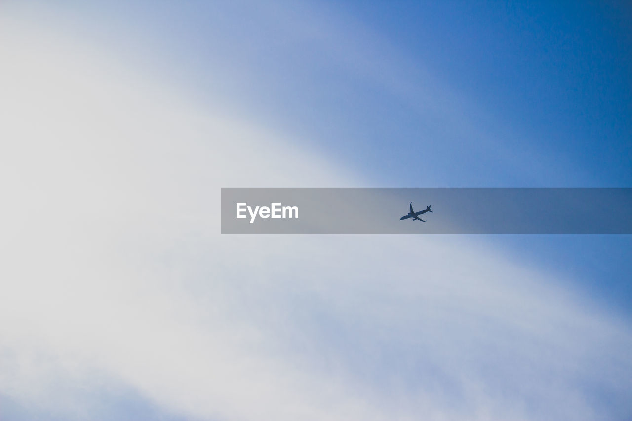 Low angle view of airplane flying against cloudy sky