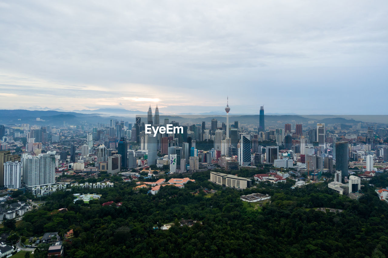 High angle view of city buildings against cloudy sky