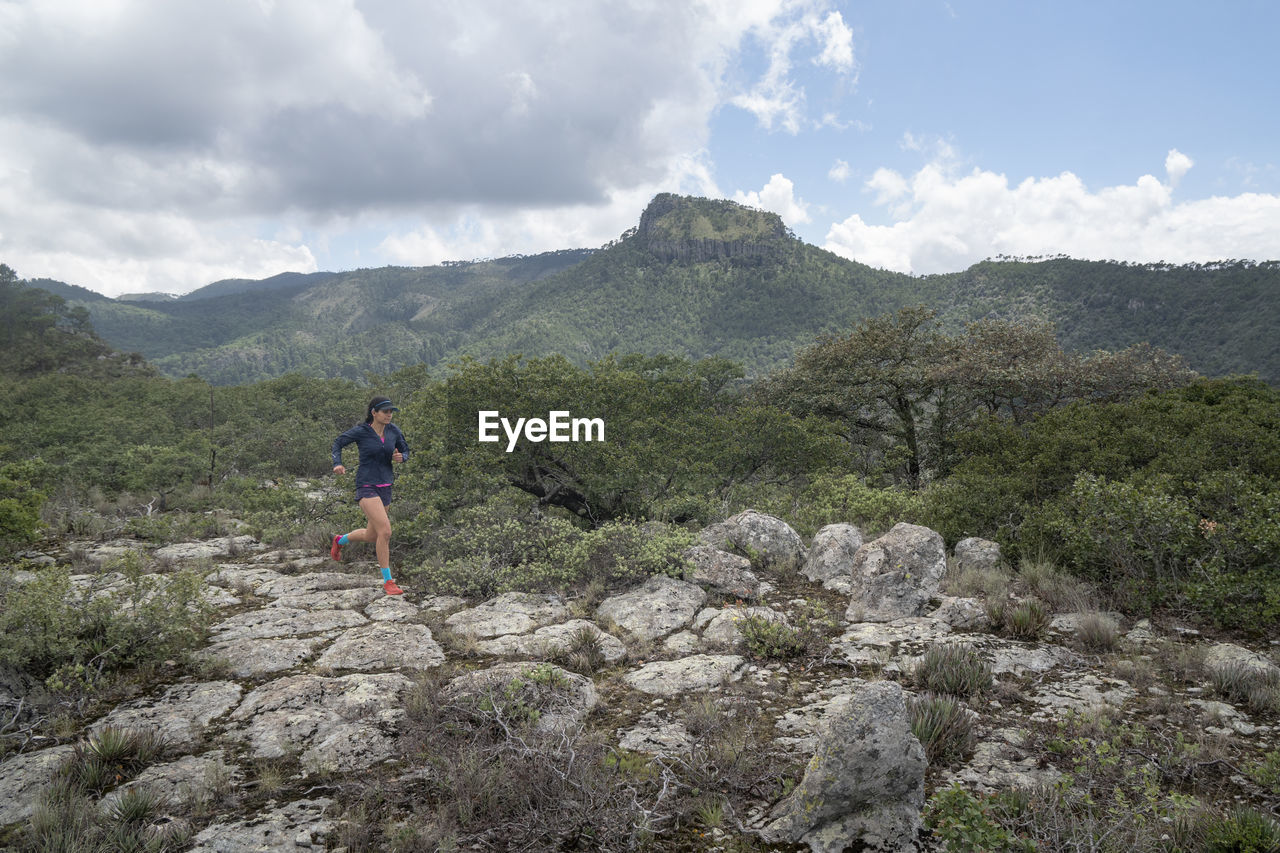 One girl trail running on a rocky surface on top of a mountain.