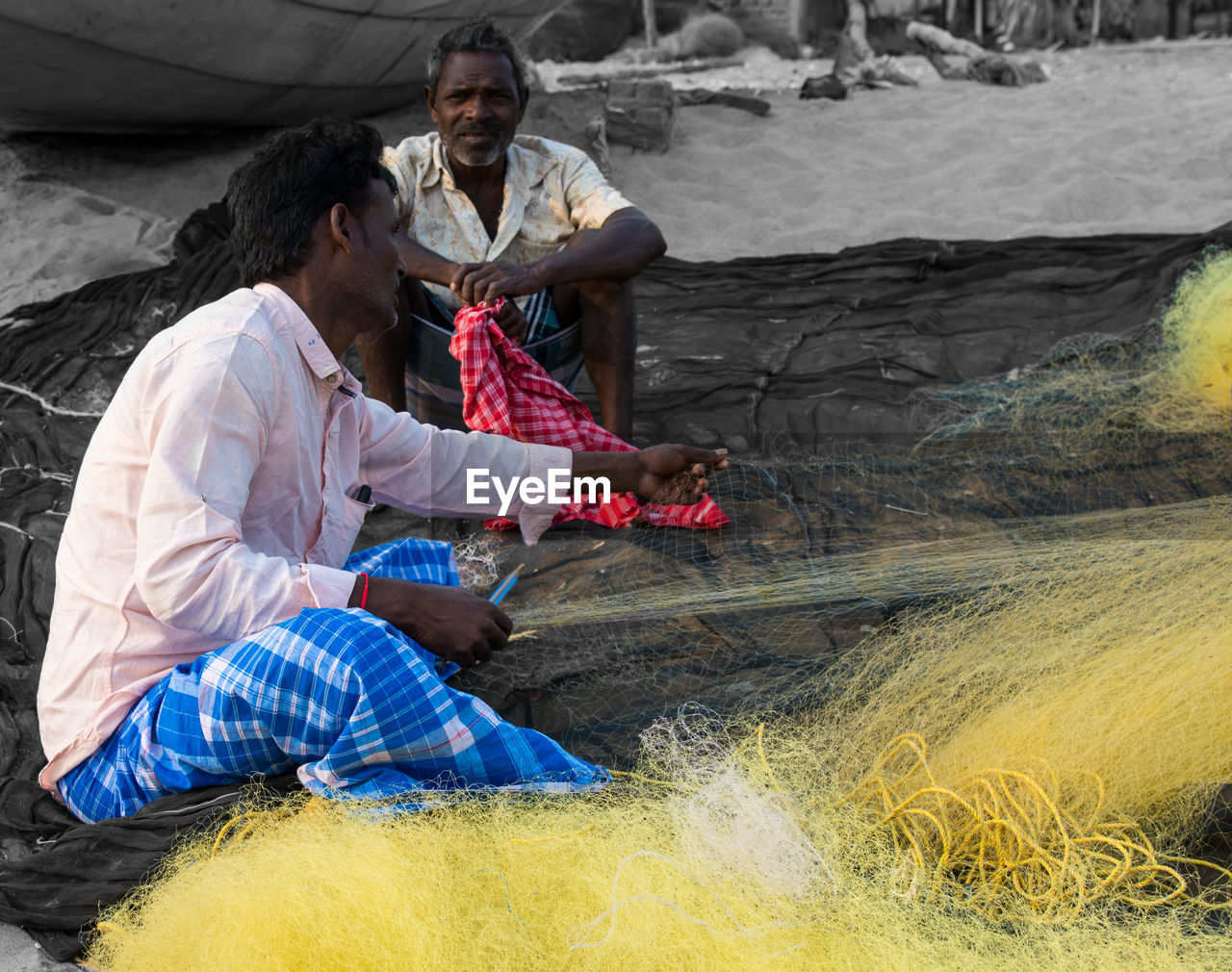 COUPLE SITTING ON ROCK AT SHORE