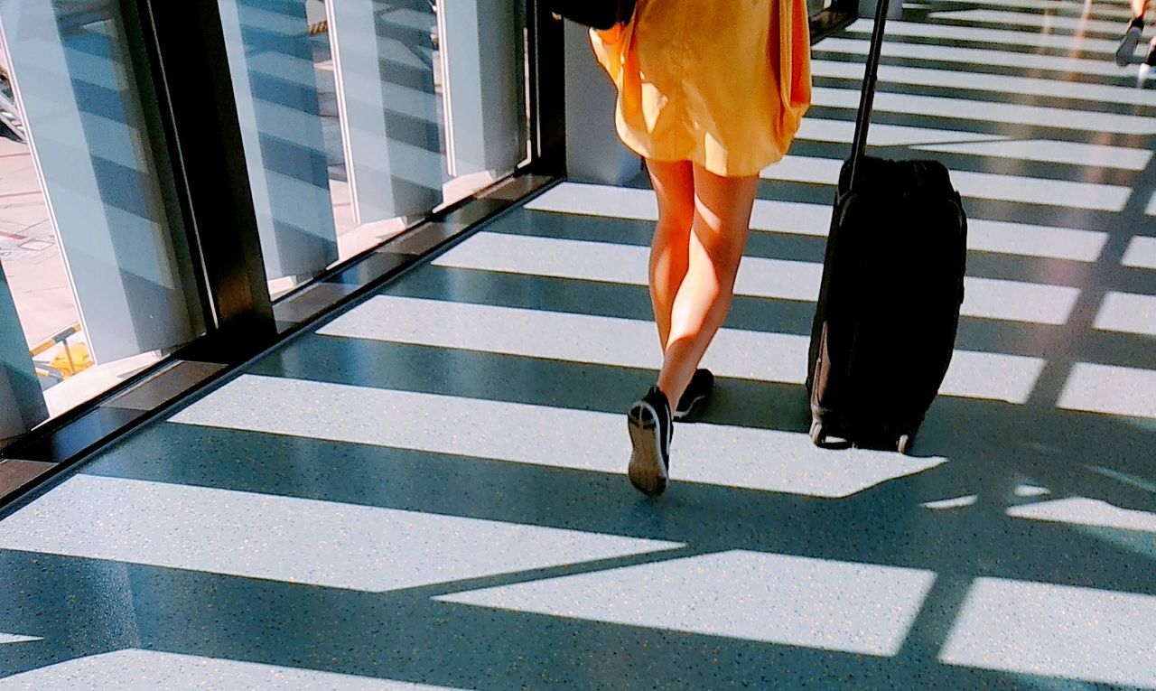 Low section of woman with luggage walking at airport